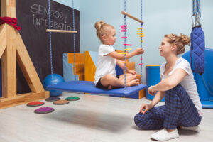 Occupational therapist assisting a child with balance and coordination using a swing.