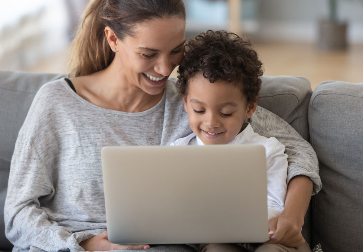 Mother and toddler using a laptop together to support AAC communication at home