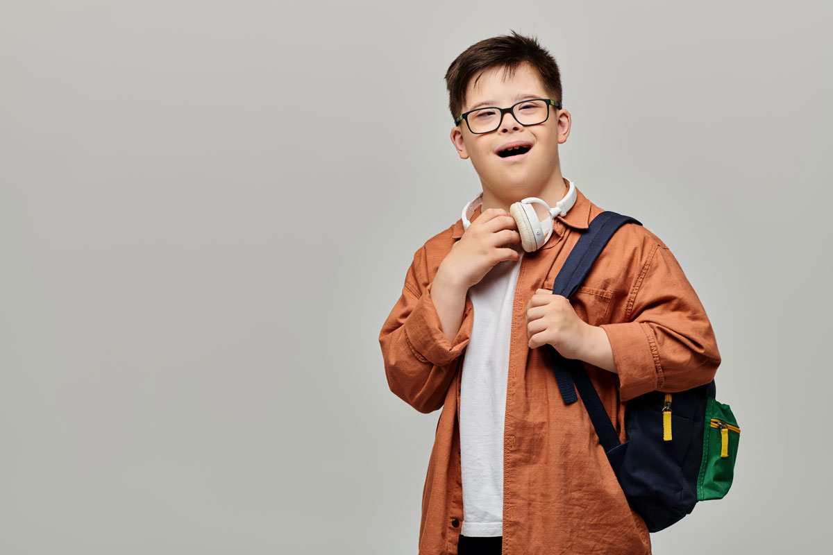 child-speech-therapy-el-paso-smiling-boy Smiling boy with headphones and a backpack, ready for pediatric speech therapy in El Paso