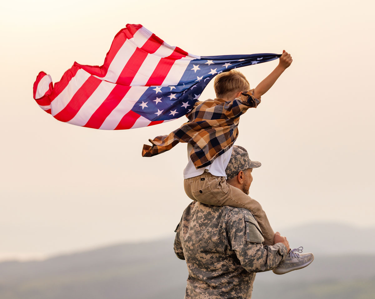 Military father carrying his child with a U.S. flag; New Beginnings supports military families in El Paso