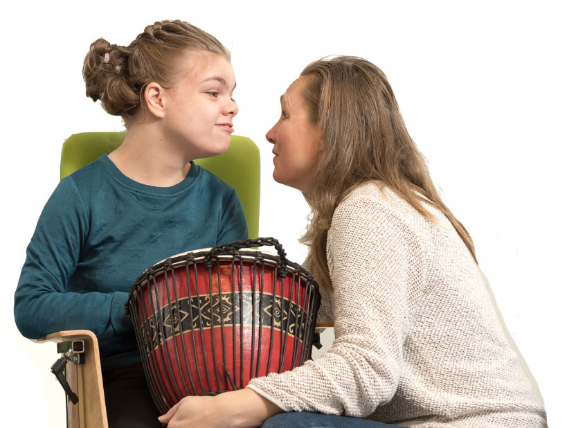 Therapist and girl playing a drum together during a one-on-one pediatric therapy session in El Paso